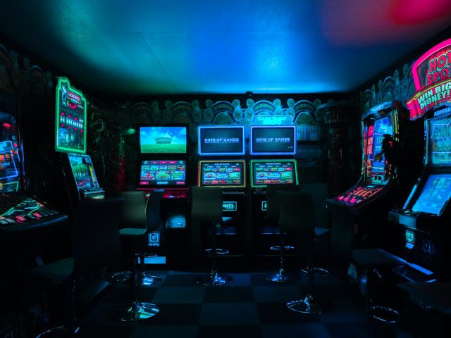 Row of lit arcade cabinets in a dark games room