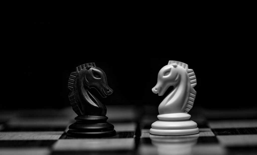 Two chess knights facing each other across a board