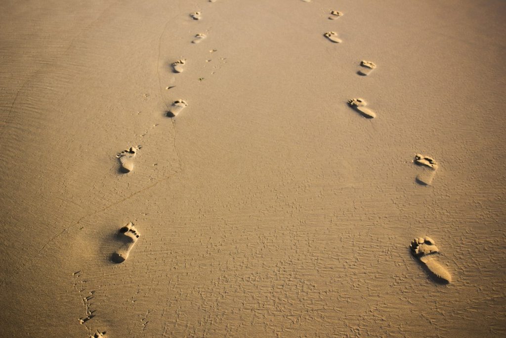 Footprints leading across brown sand