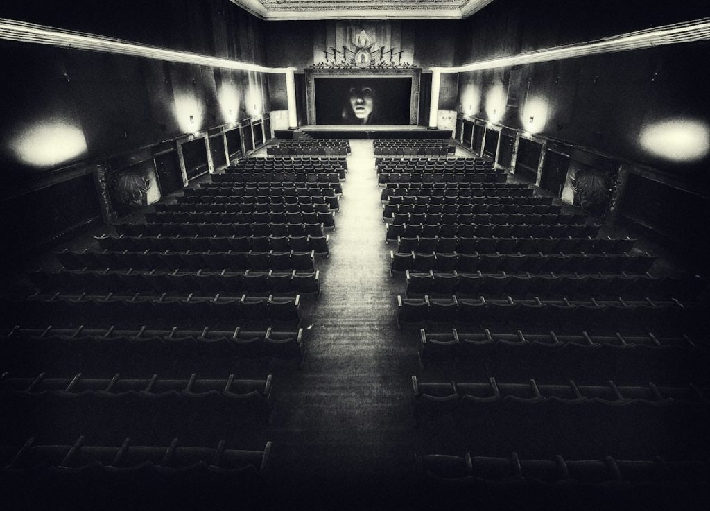 An empty vintage cinema hall facing a blank screen